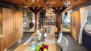 A spacious kitchen with wooden cabinets, a central island with fruit, and a stone fireplace. - Tennox Stables - UK39975 (Kilbirnie)