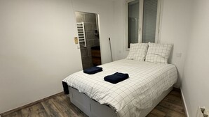 A bedroom with a bed, wooden flooring, a window, and a built-in wardrobe. - Appartement Cosy (Roussillon)