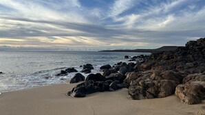 Ein Strand mit großen Felsen und blauem Himmel.
