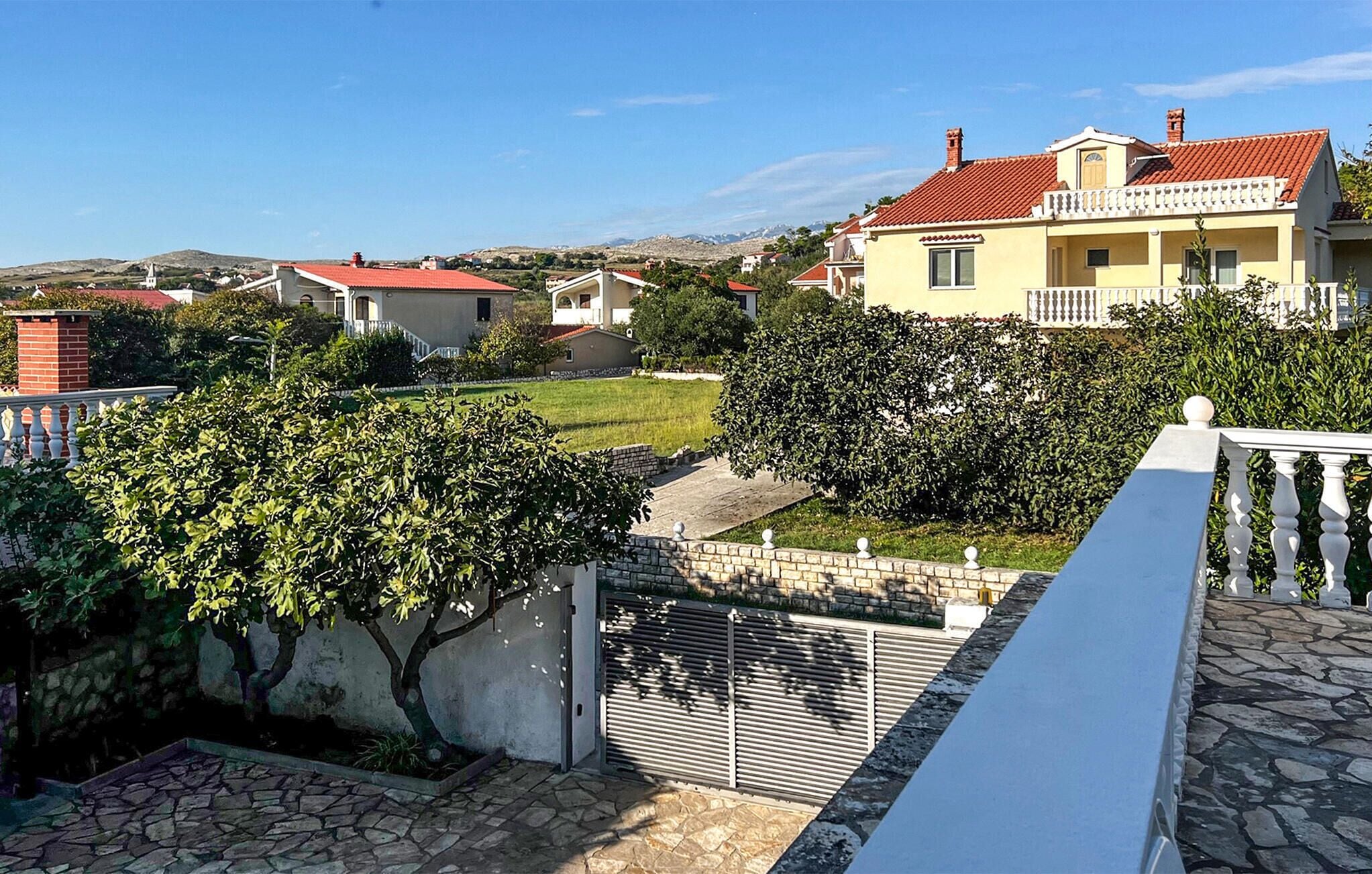 A residential area with houses, a stone pathway, and a view of distant hills.