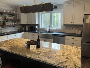 A modern kitchen with granite countertops, stainless steel appliances, and a farmhouse-style design.