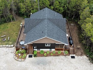 A two-story house with a sloped roof, a front porch, and a small deck area.