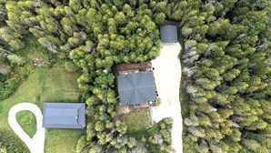 Vista aérea de uma propriedade com casa, quintal cercado e extensa área arborizada.