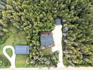 Luchtbeeld van een pand met een huis, een omheind erf en een groot bosgebied.