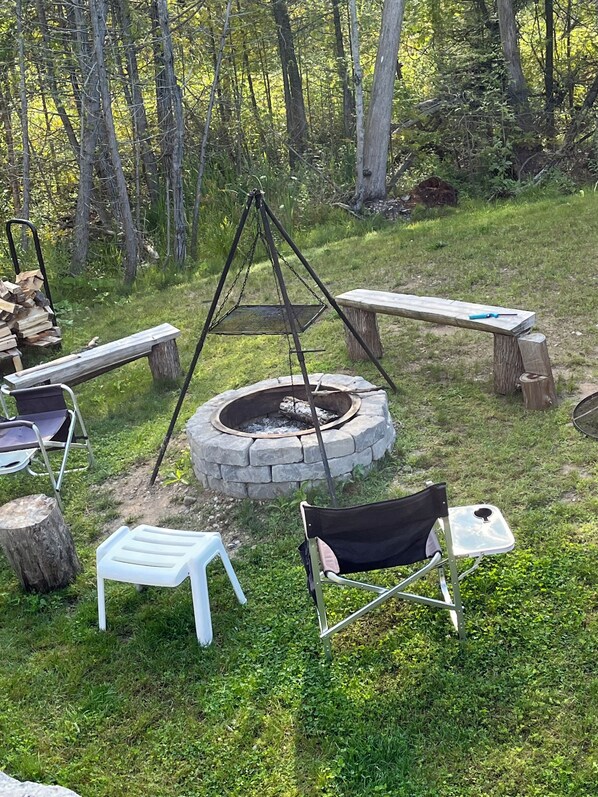 An outdoor seating area with a stone fire pit, benches, and chairs.