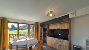 A modern kitchen with wooden cabinets, a black countertop, and a dining area with a table and chairs.