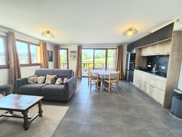 A spacious living area with a sofa, a dining table, and a kitchen area with modern appliances.