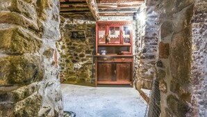 Ein schmaler Steinkorridor mit einem Holzschrank, der Glaswaren und Geschirr beherbergt.
