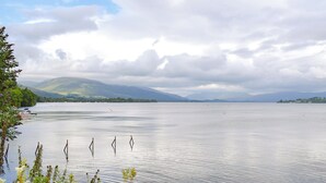 A calm lake with boats, surrounded by hills and overcast sky. - 5 bedroom accommodation in Arrochar (Arrochar)