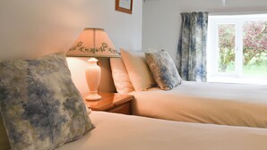 Ein Hotelzimmer mit zwei Betten, einem Nachttisch mit Lampe und einem Fenster mit Vorhängen.