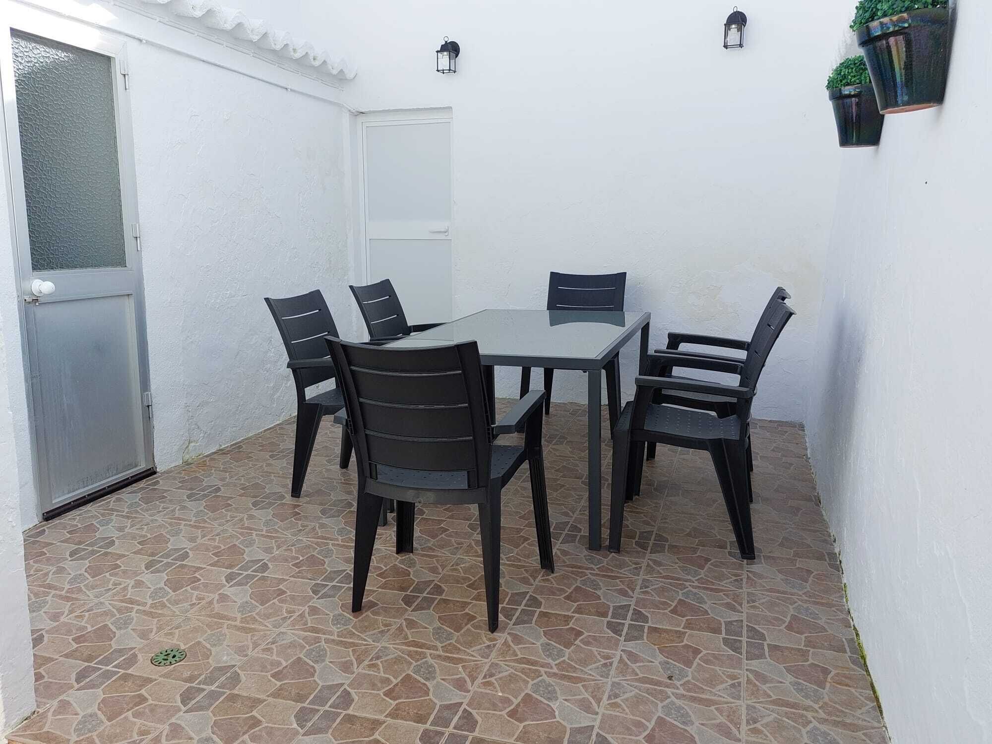 Een terras met een tafel, stoelen, een deur en een wandlamp.