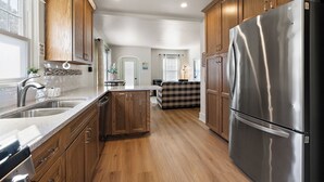 A modern kitchen with wooden cabinets, a stainless steel refrigerator, and a built-in dishwasher. - M2 -Relaxed Beach Stay • Fenced Yard, Fire Pit & 2 Living Areas, Pets welcome (Muskegon)