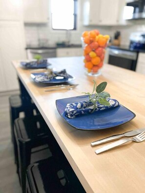 Comedor con una mesa larga dispuesta para cuatro, con platos azules y cubiertos.
