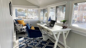Een compacte, goed verlichte kamer met een wit bureau, een blauwe stoel en een kamerkleed met een patroon.