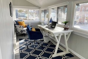 Une pièce compacte et bien éclairée, avec un bureau blanc, une chaise bleue et un tapis à motifs.