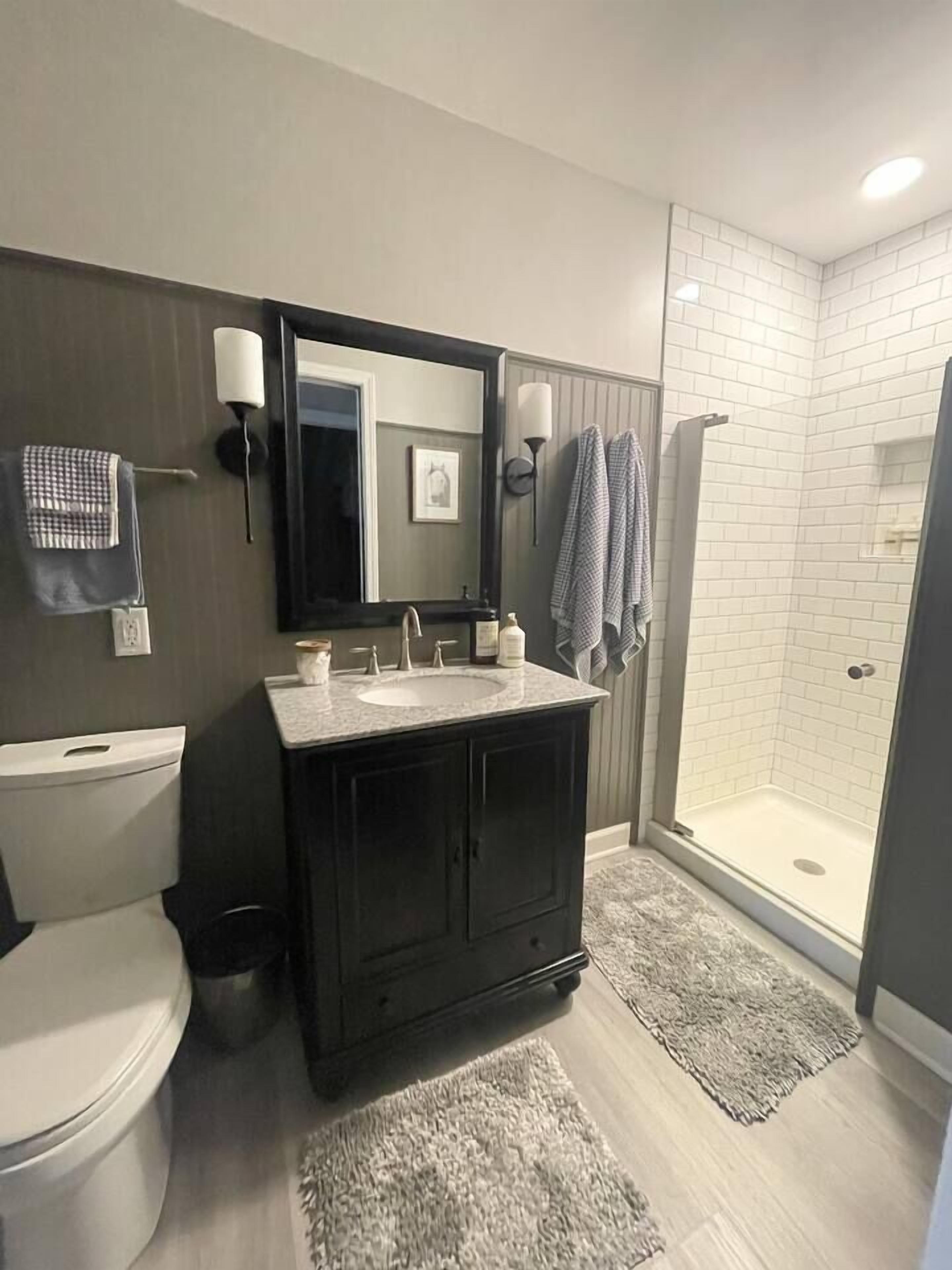 Une salle de bain comprenant des toilettes, un meuble-lavabo avec un miroir, un évier et une douche à l’italienne.