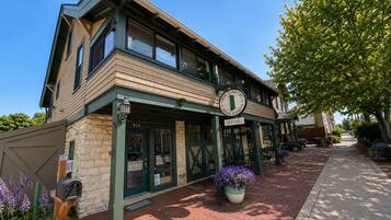 A two-story building with a green door and a sign indicating seating outside.