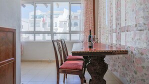 A dining area with a wooden table, two chairs, and a bottle of wine. - Gorgeous apartment in Torrevieja (Torrevieja)