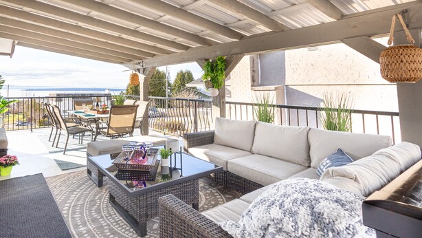 Eine überdachte Terrasse im Freien mit Rattanmöbeln, einer Couch und einem Essbereich.