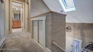 A hallway with a ceiling skylight, a textured wall, and a door with a towel rack.