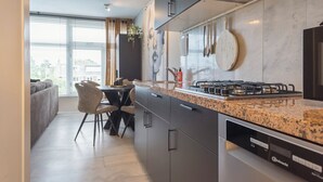 Et moderne køkken med en granitbordplade, stålstål-hvidevarer og et spiseområde med en sofa og stole.