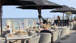 En restaurant ved havet med udendørs siddepladser, borde og parasoller.