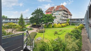 En flereetagers boligbygning med en gårdsplads, et overdækket cykelområde og en trappe op til en øvre etage.