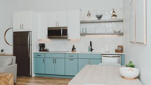 Eine moderne Küche mit weißen Schränken, einem Edelstahlkühlschrank und einem Holztisch.