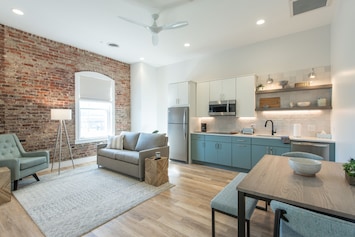 Open living area with full kitchen, dining area, work desk, and queen sleeper.