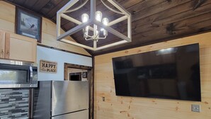 Una cocina moderna con paneles de madera, electrodomésticos de acero inoxidable y un televisor de pantalla plana grande montado en la pared.