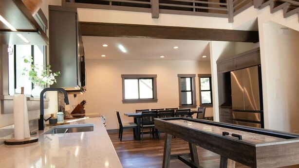 Una cocina moderna con barra, piso de madera y comedor con mesas y sillas.