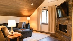 Una sala de estar acogedora con chimenea, un sofá, una lámpara y una ventana con cortinas.