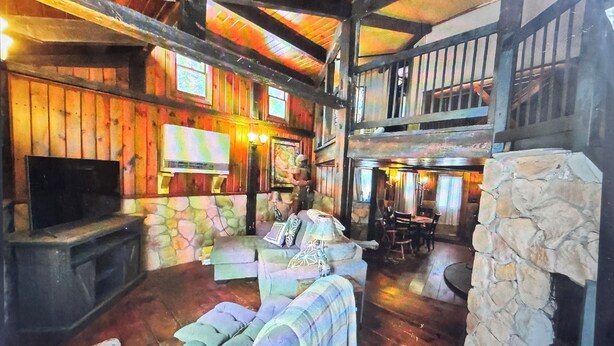 A spacious interior with a stone fireplace, wooden beams, and a television.