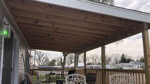 Un portico coperto con travi in legno, mobili da esterno e vista sulle case vicine.