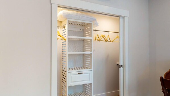 Um closet amplo com prateleiras abertas, barra para pendurar roupas e porta branca.