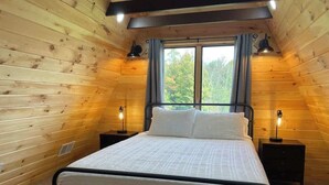 Ein Schlafzimmer mit einem Bett, zwei Nachttischen und einem Fenster mit Vorhängen.