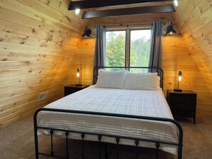 Un dormitorio con cama, dos mesitas de noche y una ventana con cortinas.
