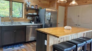 Eine Küche mit einer Holzinsel, Barhocker, einem Kühlschrank und einem Spülbecken.