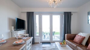 A living room with a television, dining table, and a sofa. - Marlene with parking and shared pool by Interhome (De Haan)