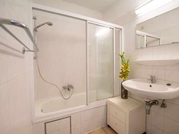 Un baño moderno con cabina de ducha de vidrio, un lavabo blanco y un espejo encima.