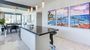 Una cocina moderna con una isla central, iluminación colgante y obras de arte en las paredes.