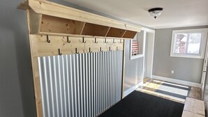 A room with a wooden coat rack, a black carpet, and a window with blinds.