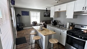 A modern kitchen with a central island, bar stools, a stove, and a refrigerator.