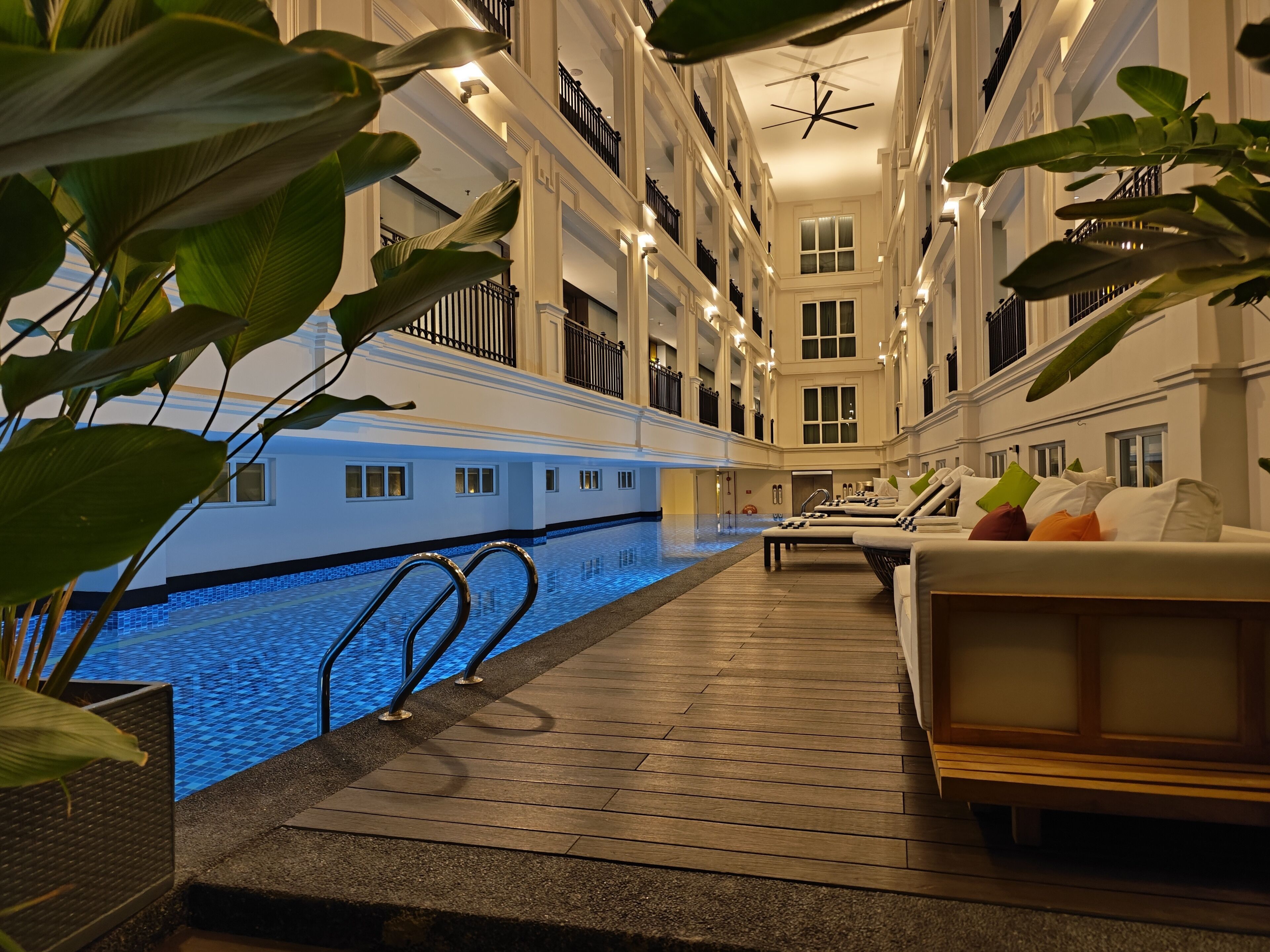 A hotel interior with a swimming pool, lounge areas, and balconies.