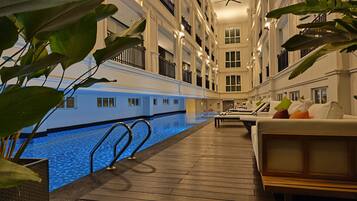 A hotel interior with a swimming pool, lounge areas, and balconies.