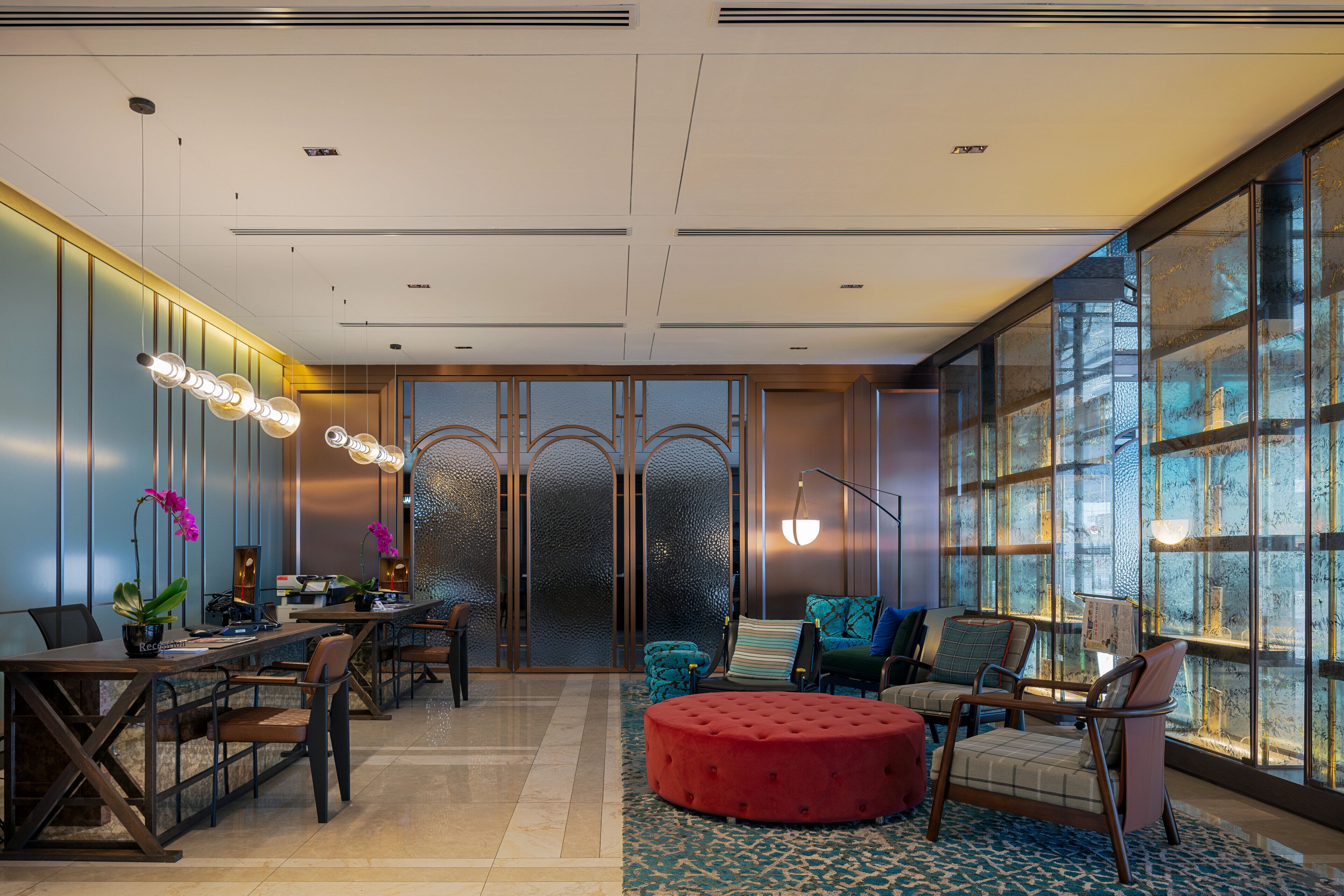 Un moderno vestíbulo de hotel con un mostrador de recepción, zona de estar y grandes ventanales con vistas.
