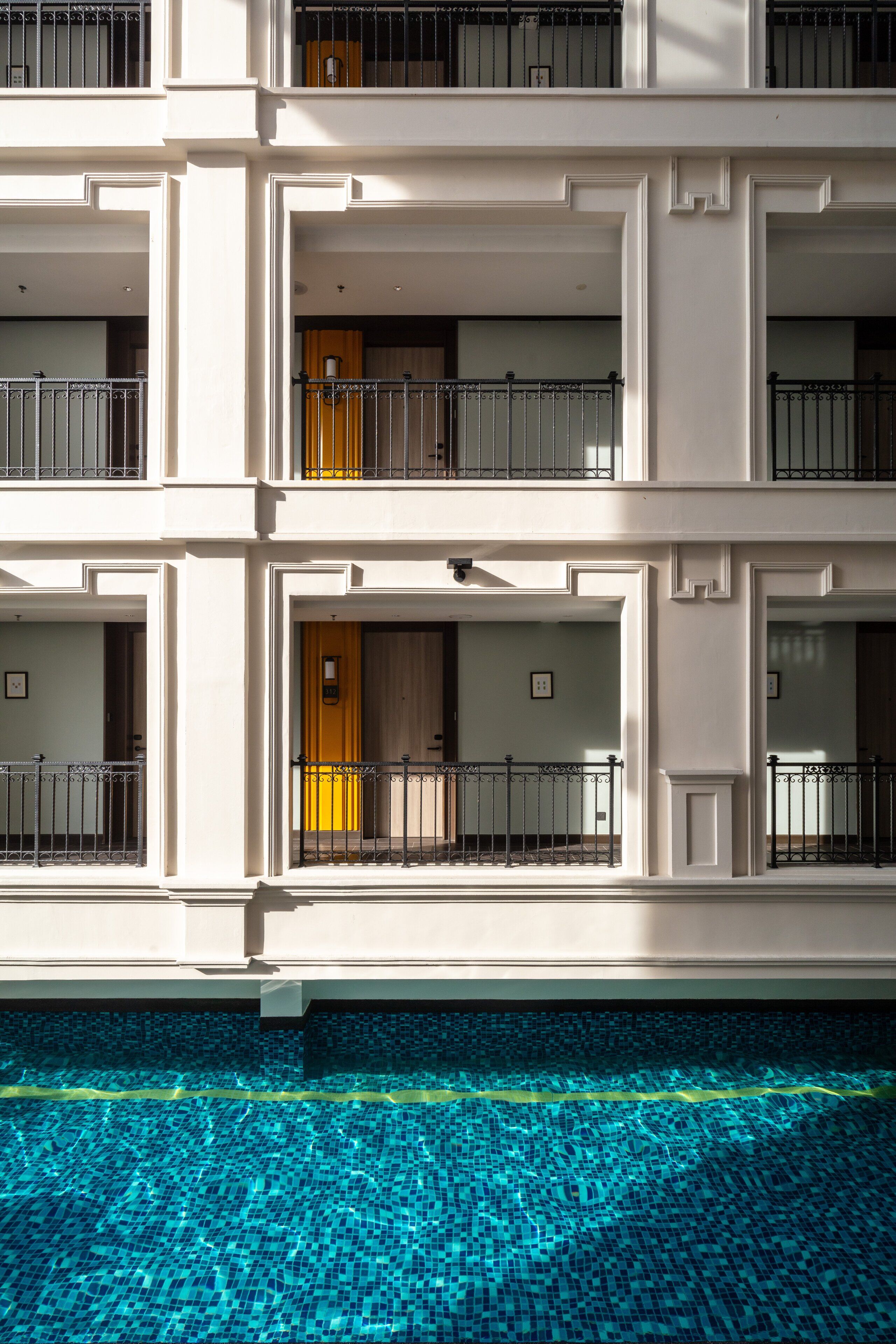 A multi-story hotel with balconies, a swimming pool, and a modern architectural design.