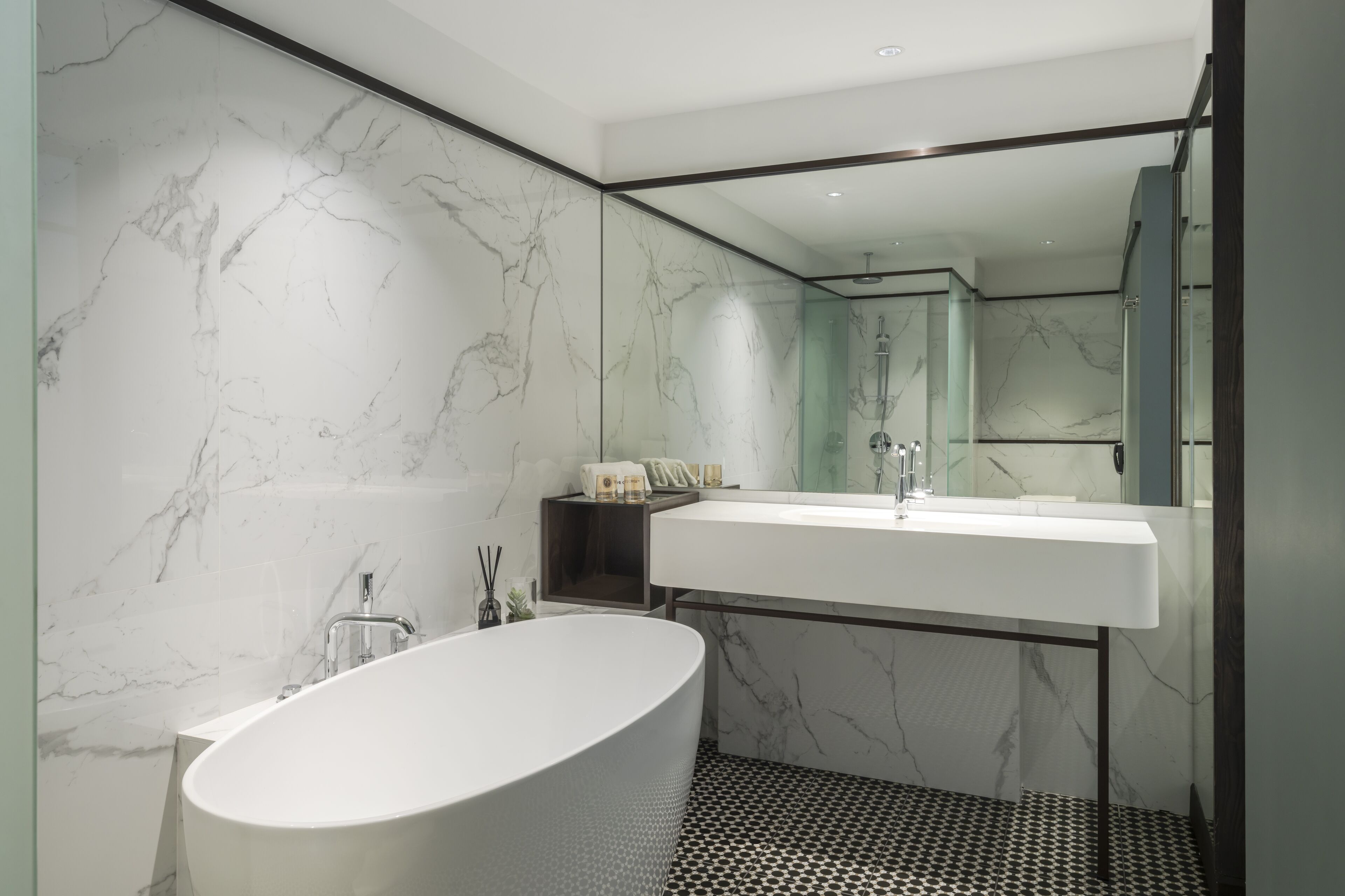 A modern bathroom with a freestanding bathtub, a large mirror, and a white sink.