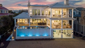 Una casa a due piani con piscina, ampie finestre e patio coperto.