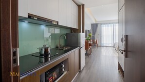 A modern kitchen with a built-in stove, sink, and a dining area with a table and chairs. - Maihomes hotel & Serviced Apartment (Vinh Phuc)